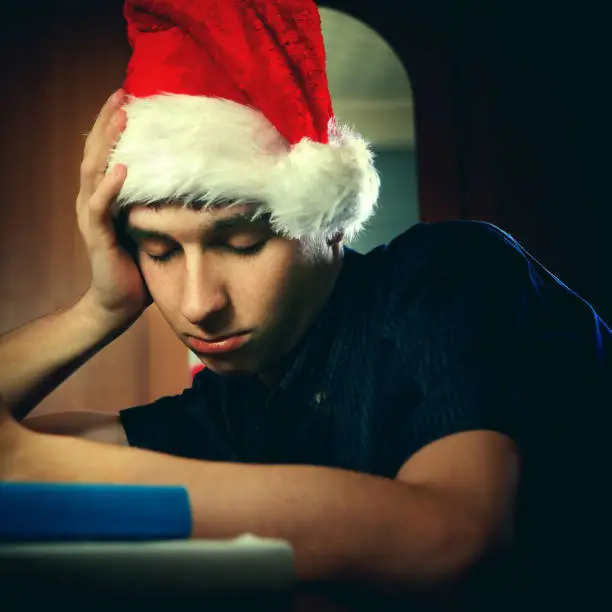 Toned Photo of Tired Young Man in Santa's Hat sleeping
