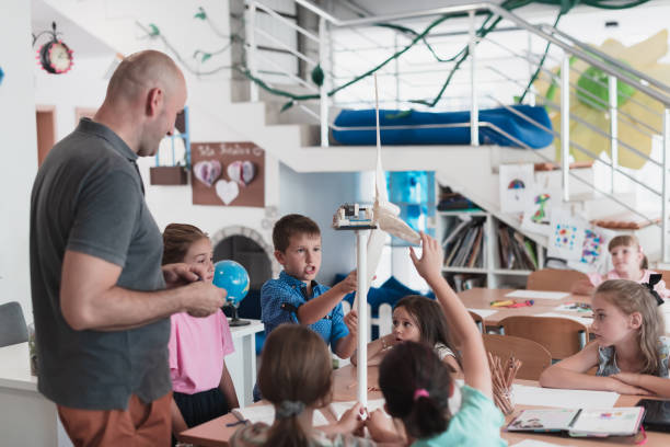 istock Elementary School Stem Robotics Classroom Diverse Group of Children Building and Programming windmill ecology robot concept. Together Talking and Working as a Team. Creative Robotics Engineering 1411355163