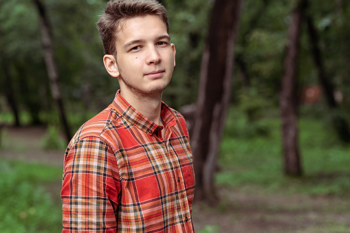 portrait of handsome young man in red plaid shirt looking at camera