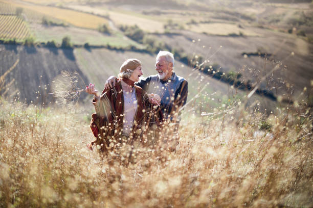 istock Happy mature couple talking while walking through tall grass in nature. 1411356590