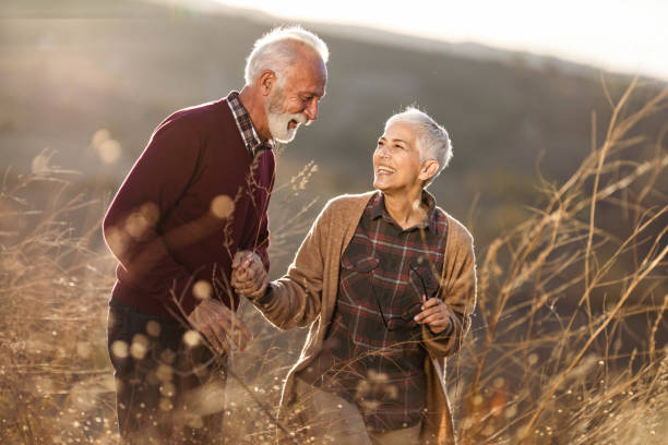 istock Cheerful mature couple talking while walking through tall grass in nature. 1411356720