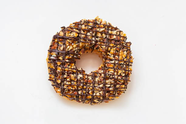 istock Chocolate donut with frosted glazed and nuts sprinkles top view isolated on white background. Dessert and sweet food concept. Top View. 1411357030