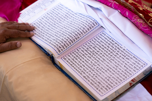 Guru Granth Sahib Holy Religious Scripture of Sikhism. Punjabi language written on religious white pages in wedding ceremony.