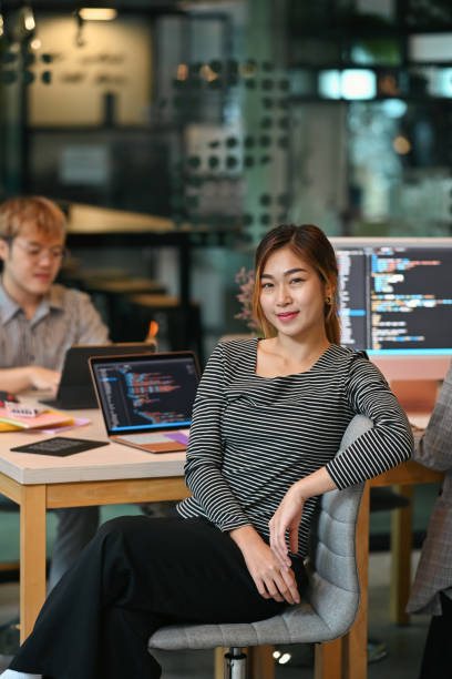 istock Young female software developer sitting in start up office with co working atmosphere. 1411360770