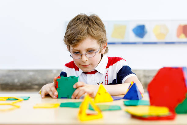 istock Happy kid boy with glasses having fun with building and creating geometric figures, learning mathematics and geometry 1411360852