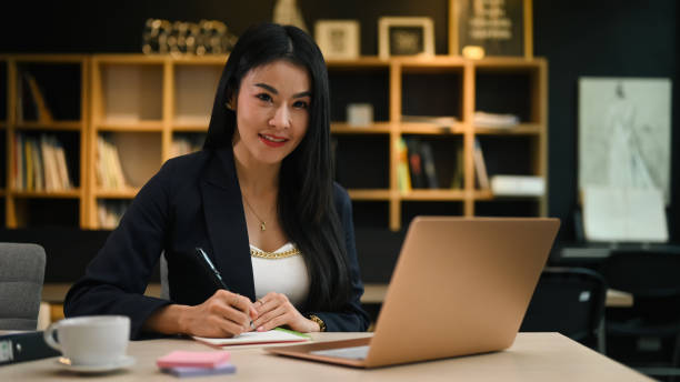 istock Charming millennial businesswoman working with laptop and making notes on notepad. 1411360945