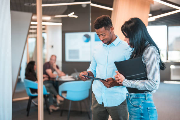 istock Multiracial Attractive Man and Latin Woman Using Digital Tablet in Office Corridor 1411362475