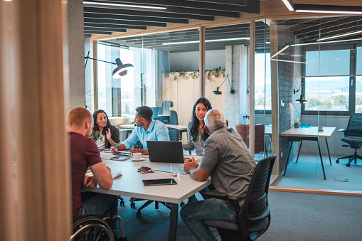 Indoor shot of hard working colleagues seated at an open concept office. They are planning next year business strategy to present to the main board.