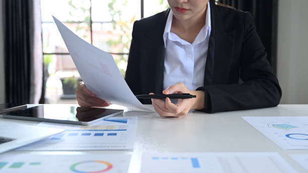 istock Focused female economist working with statistics document at office desk. 1411362775