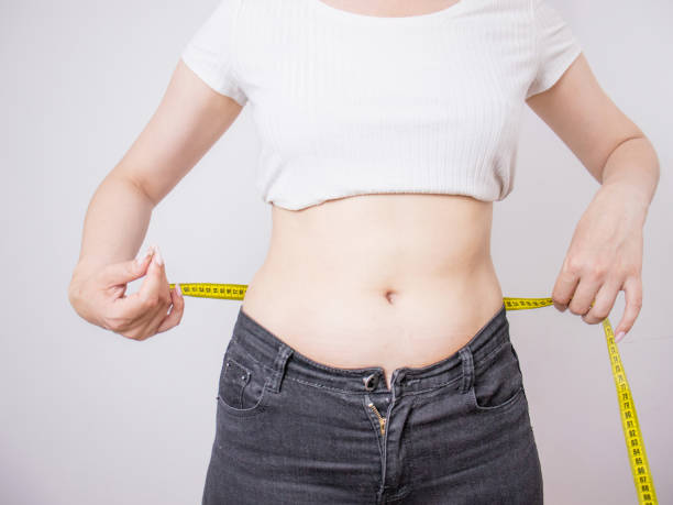woman makes a measurement of the waist with a centimeter tape woman makes a measurement of the waist with a centimeter tape, waist,fat belly female navel stock pictures, royalty-free photos & images