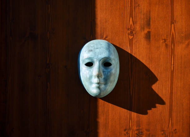 istock Venetian mask on wooden background with high contrast shadow 1411365728