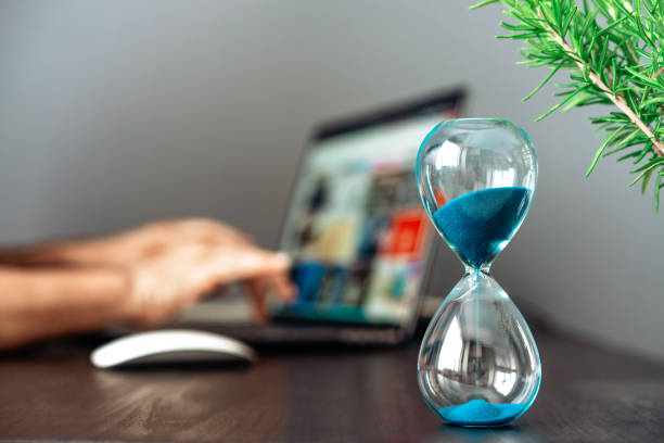 istock Hourglass with blue sand on the desk 1411365781