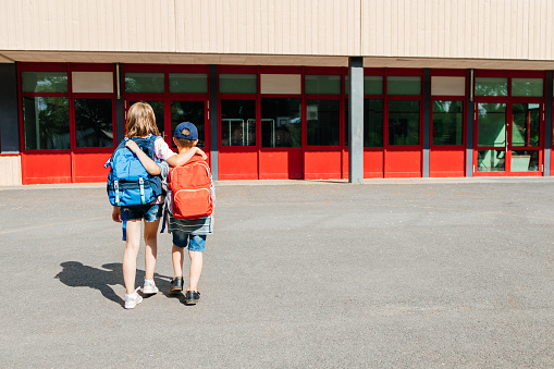 Back to school. Brother and sister with backpacks on their backs go to school in an embrace. Beginning of the school year.