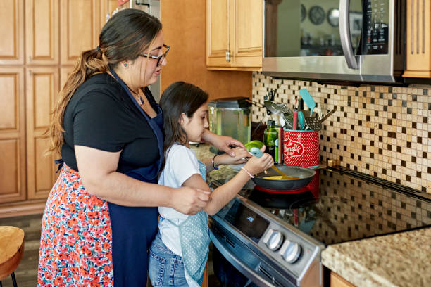 istock Latin American mother teaching daughter how to scramble eggs 1411368448