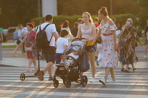 Moscow, Russia - July 23 2022: People on the Moscow city street in hot summer day. A lot of people. They are crossing the pedestrian cross walk. Modern lifestyle concept. Modern young mother with baby
