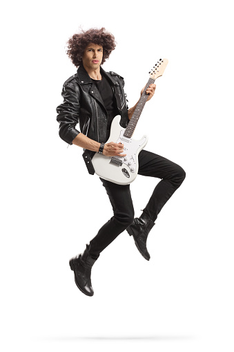 Male rock star playing a guitar and jumping isolated on white background