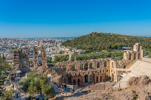 ATHENS, GREECE - MAY 21, 2022: The Odeon of Herodes Atticus on the Acropolis of Athens, in the background the Philopapposmonument