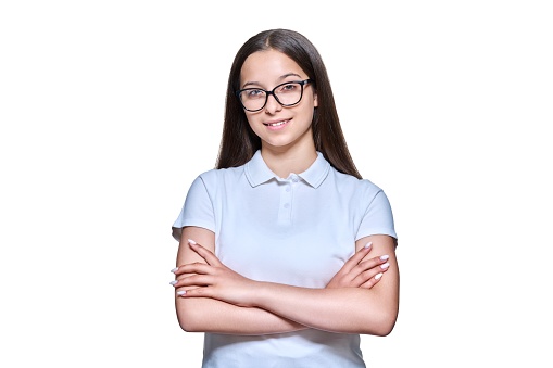 Confident teenage girl high school student looking at camera on white isolated background. Attractive female in glasses posing with crossed arms. Adolescence, study, education concept