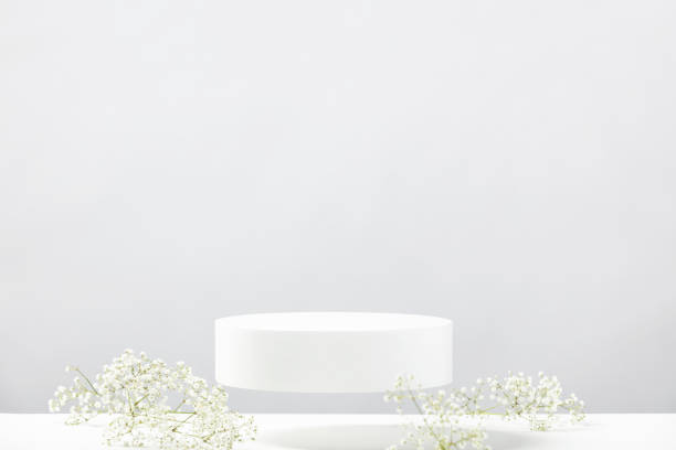 istock Flying empty white podium and white flowers on grey background. Mock up stand for product presentation. 3D Render. Minimal concept. 1411375301