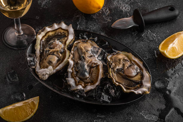 istock Fresh oysters close-up on ice served with lemon and wine. 1411375913