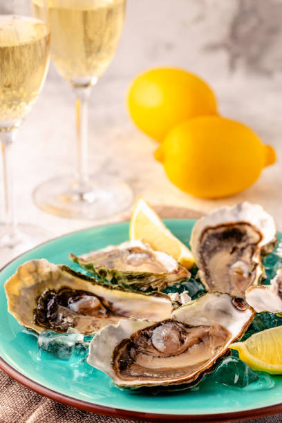 istock Opened fresh oysters on a blue plate, served with lemon and ice. 1411376044