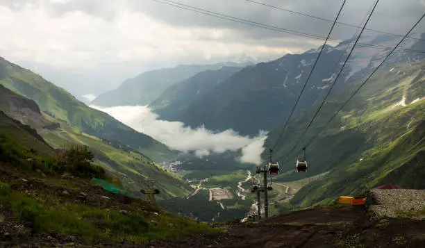 panoramic landscape - top view - Cable car with cabins rising and descending high in the Caucasus mountains among the rocks and slopes on a cloudy day in elbrus region