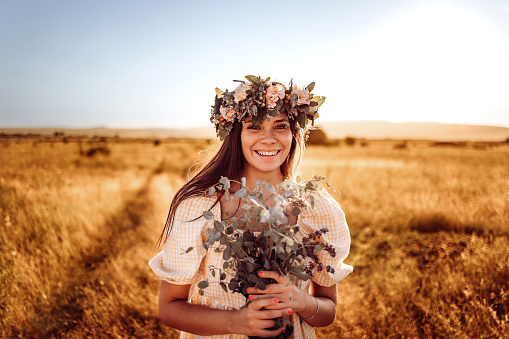 Happy young beautiful woman wearing flower garland in fields