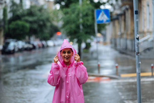 istock Young smiling woman with raincoat while enjoying a rainy day. 1411381244