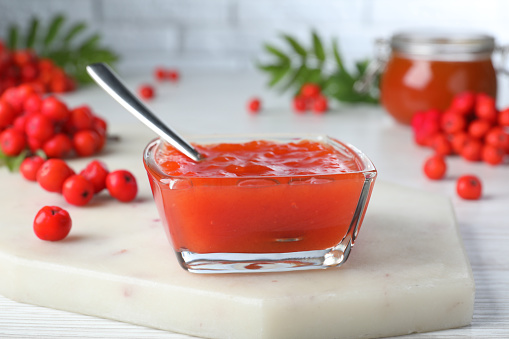 Delicious rowan jam in glass bowl on white wooden table