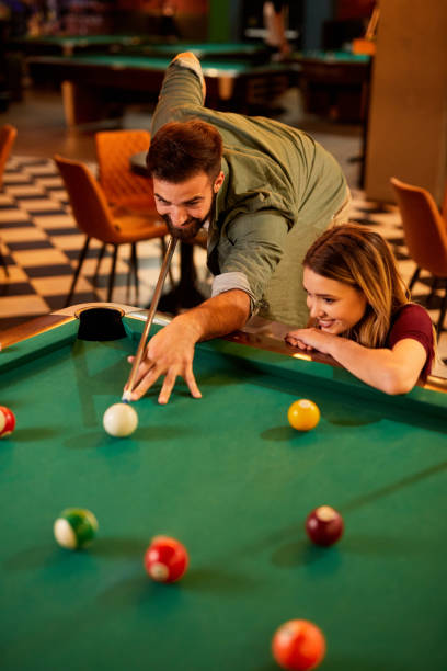 istock Young happy couple enjoying playing billiard on a date in pool hall 1411384094