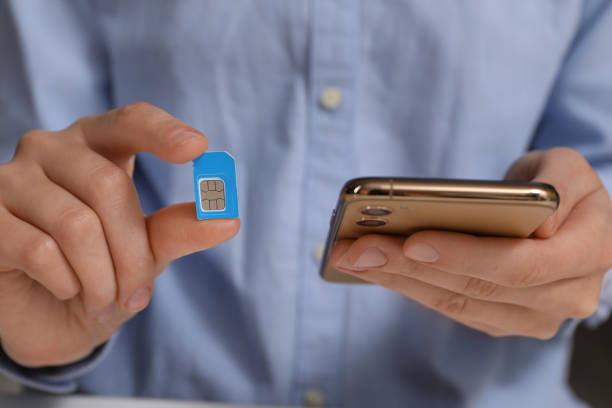 istock Woman with SIM card and smartphone, closeup 1411385342