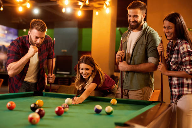 Group of friends having fun while playing pool in a local pool hall stock photo