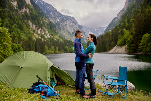 Embraced couple relaxing near a lake while camping