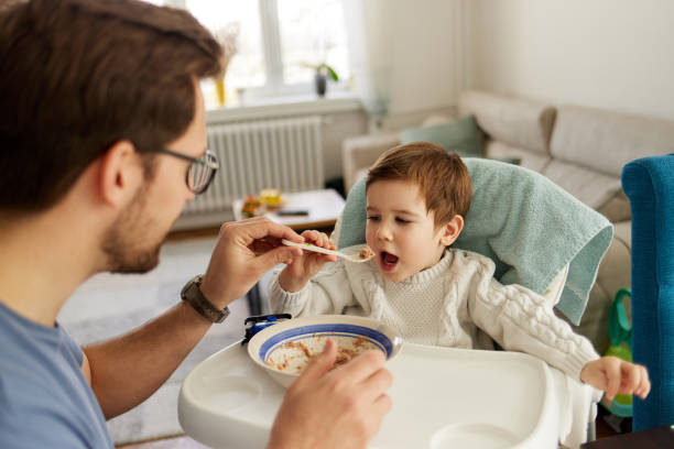 istock Caring single father spoon feeding his beautiful son 1411386020