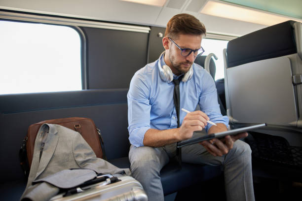 istock Businessman working on digital tablet while travelling by the train 1411386489