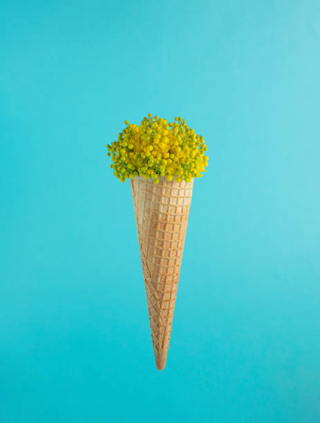 istock Ice cream cone with small yellow and green flowers on a light blue background. 1411386590