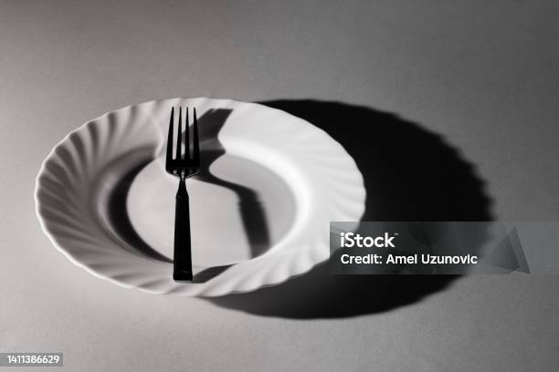 One Fork In A Plate With Shadows And Textures Black And White Minimal Creative Surreal Concept Eat Eating Utensil Emptiness Loneliness Stock Photo - Download Image Now