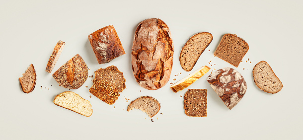 Fresh bread creative layout on bright background. Whole and sliced breads composition. Healthy eating and dieting food concept. Top view, flat lay. Design element. Color card