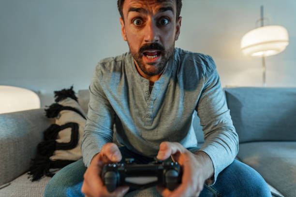 excited and overemotional man playing video games at home - overemotional imagens e fotografias de stock