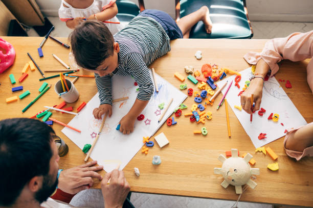 Boy Drawing And Colouring With His Father