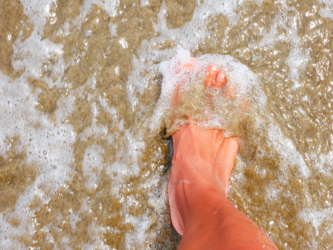 Beautiful photo of bare feet of a black person in the sea