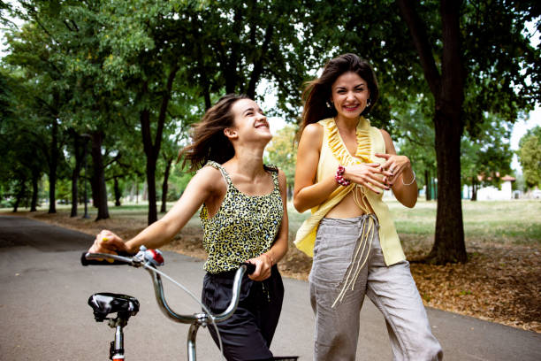 Two women having fun with a bicycle at park