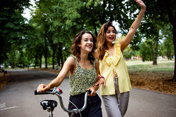 istock Two women having fun with a bicycle at park 1411389466
