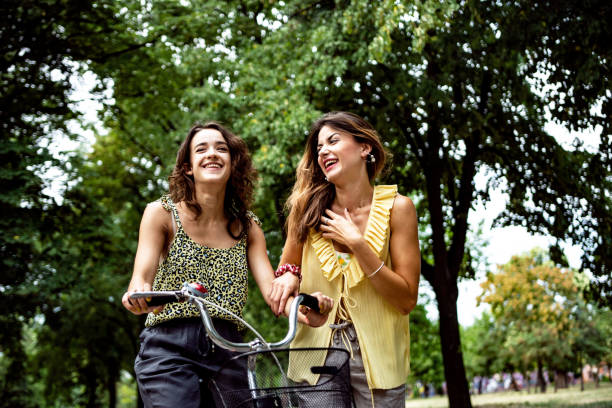 istock Two women having fun with a bicycle at park 1411389474