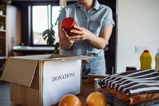 Close up of a woman in blue shirt holding a jar and packing a donation box