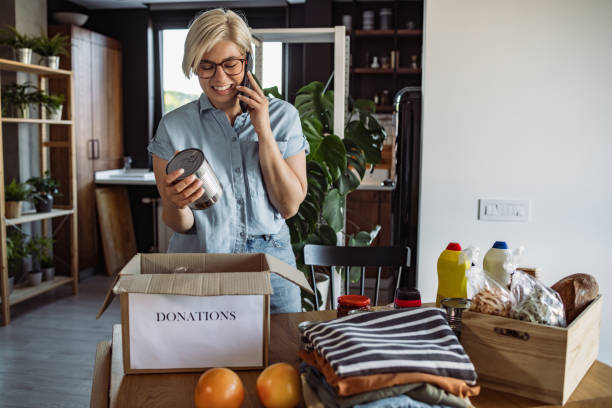 istock Young woman packing a donation box while talking on the phone 1411396703