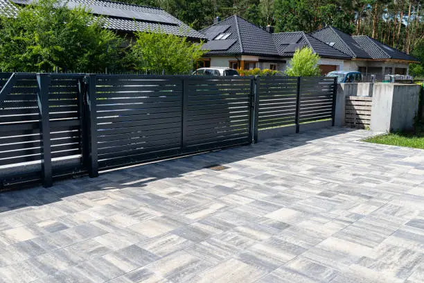 Photo of Modern panel fencing in anthracite color, visible sliding gate to the garage as well as a handle and a lock.