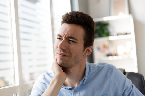 istock Feeling exhausted.Frustrated young man looking exhausted and massaging his neck while sitting at his working place 1411399665