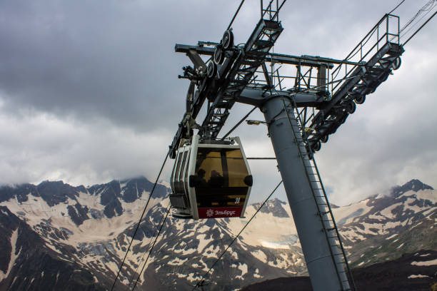 teleférico con cabinas que suben y bajan en lo alto de las montañas del cáucaso - overhead cable car summer ski lift scenics fotografías e imágenes de stock