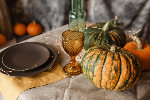 istock Autumn interior: a table covered with dishes, pumpkins, a relaxed composition of Japanese pampas grass. Interior in the photo Studio. Close - up of a decorated autumn table. 1411400998